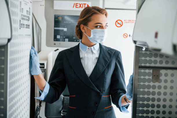 istock In mask. Young stewardess on the work in the passanger airplane 1365848579