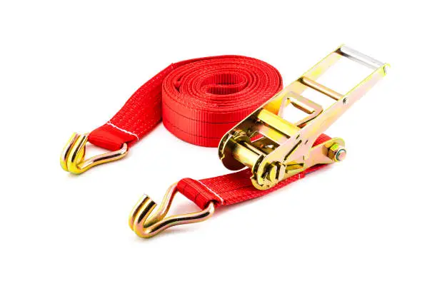 Photo of Trailer strop or strap in orange nylon and metal tie isolated over white background. Ratchet straps for cargo load control. Cargo restraint strap