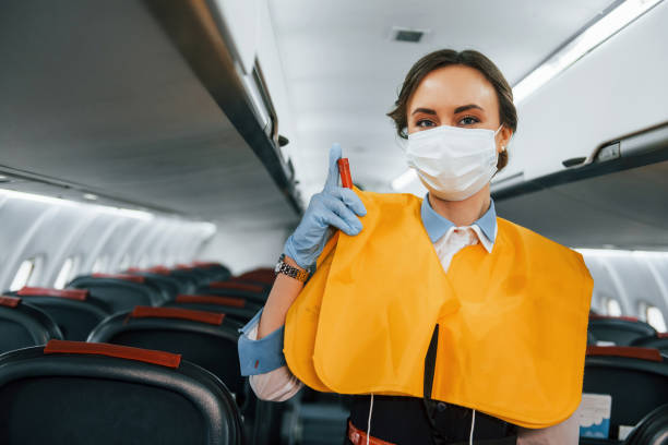 istock Safety instructions. Young stewardess on the work in the passanger airplane 1365848685