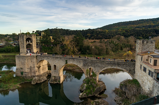 View of Besalú medieval bridge above Fluvià river in a cloudy day at 12 06 2021 in Besalú Village, Gerona Province in Spain