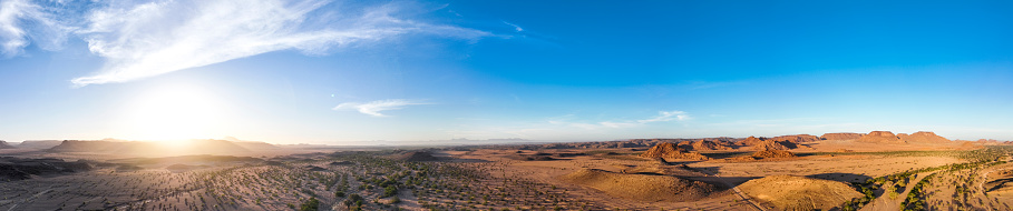 180 degree panoramic sunrise across vast desert landscape  blue sky with some clouds