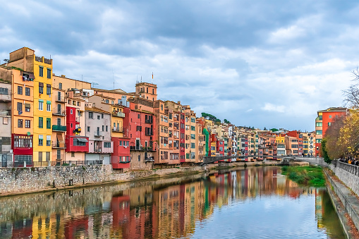 Landscape of Girona with Gomez or Princess Bridge over the river Onyar, Spain. Town panorama with bright multi-colored old houses and their reflections in the water stream