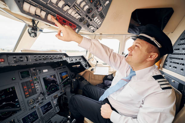 istock Professional worker. Pilot in formal wear sits in the cockpit and controls airplane 1365852042