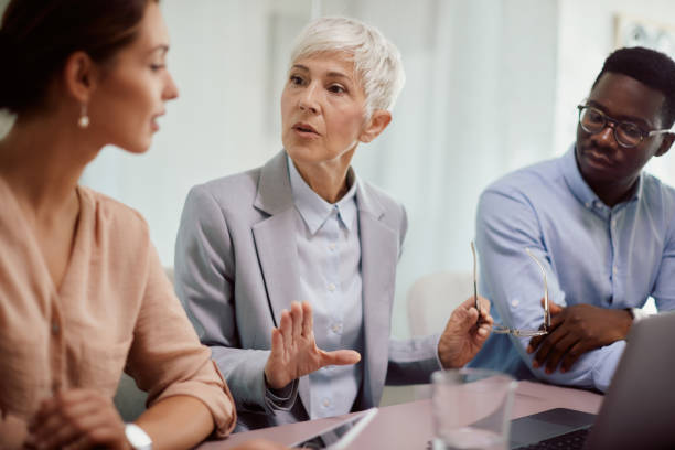 istock Senior CEO talking to her young colleagues while using laptop during the meeting. 1365855562