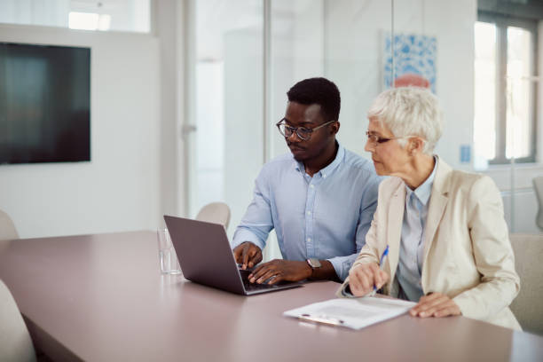 istock Business coworkers cooperating while working on laptop at corporate office. 1365855573