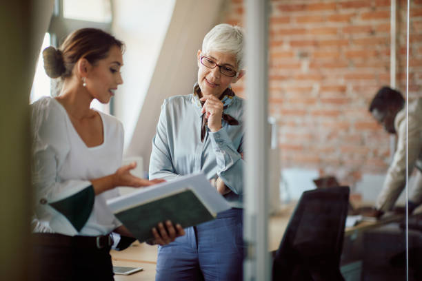 istock Senior business leader analyzing documents with her assistant at corporate office. 1365855687