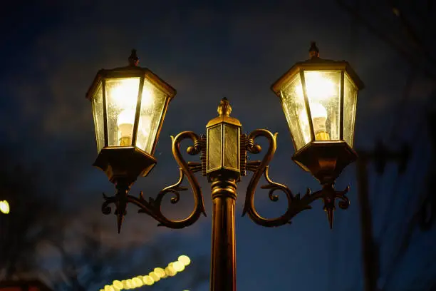 Photo of Old vintage street lamp on the road at night.