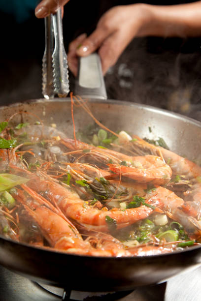 istock Chef preparing prawn in a pan on a stove 1365857201