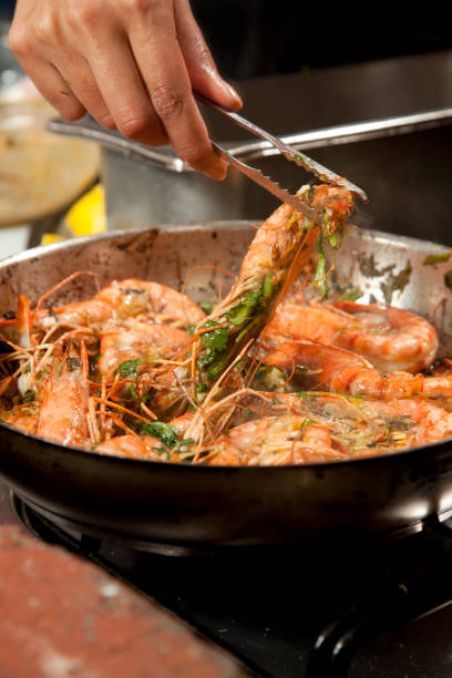 istock Chef preparing prawn in a pan on a stove 1365857259