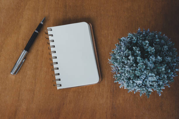 istock Notebook blank and pen and flower on vintage wood table background.Top view with copy space. 1365858486