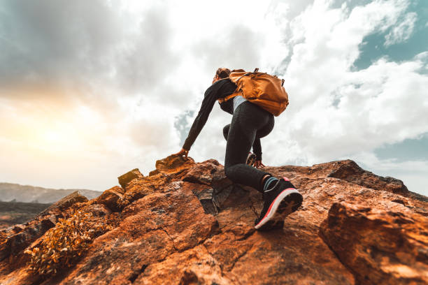 Success woman hiker hiking on sunrise mountain peak - Young woman with backpack rise to the mountain top. Discovery Travel Destination Concept stock photo