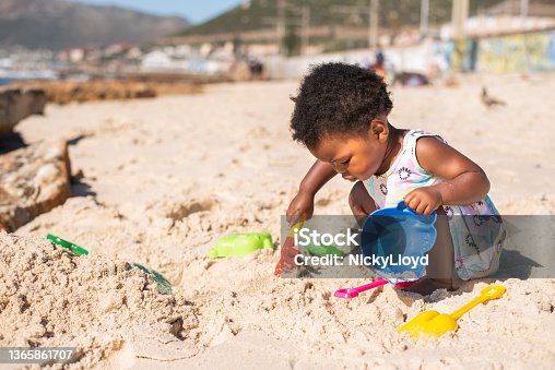 istock Little girl playing with a sand pail and shovel at the beach 1365861707