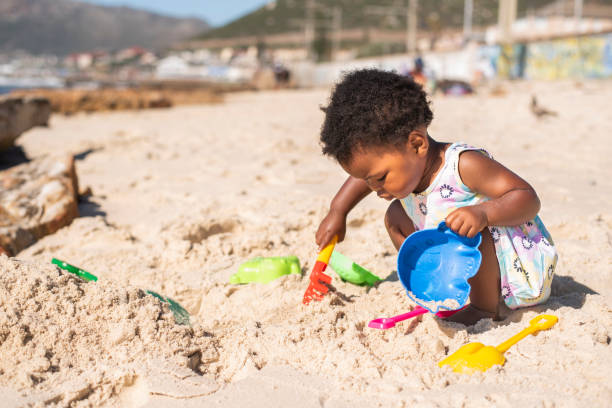 Little girl playing with a sand pail and shovel at the beach stock photo