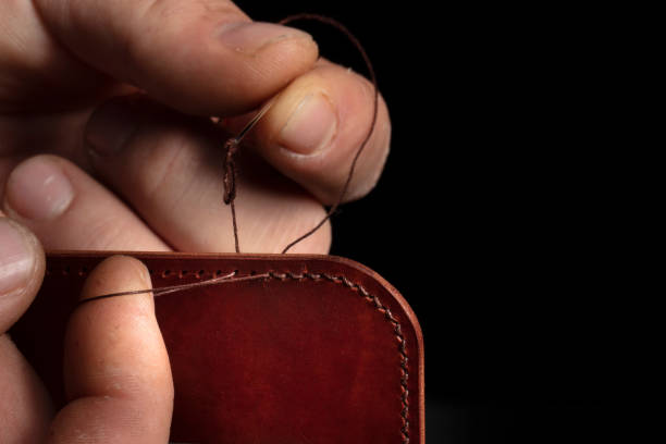 istock Making leather wallets. The hands of the master sew a leather product. 1365861752