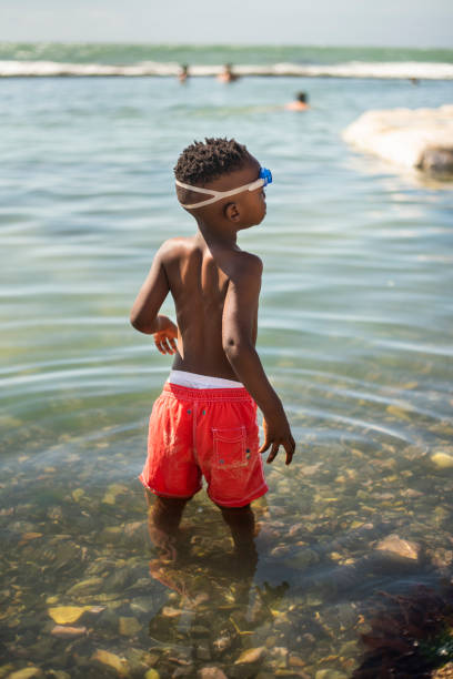 istock Little boy standing in the sea during a summer beach trip 1365862888