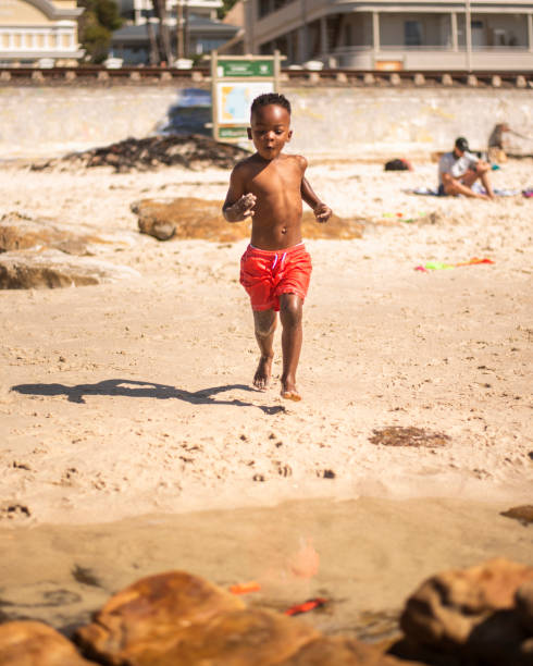 istock Cute little boy running running on a beach toward the sea 1365863309