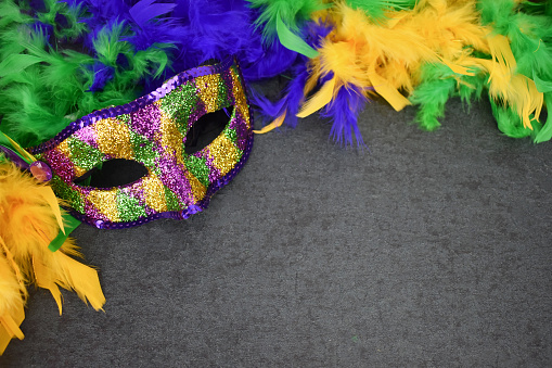 Mardi Gras Holiday Carnival Mask and Feather Boa Over Blackboard Background with Copy Space