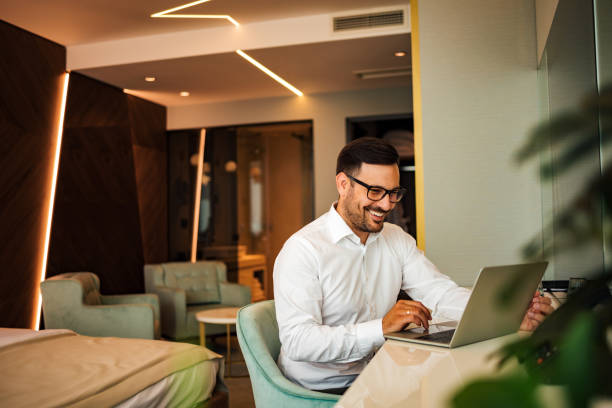 elegant smiling man using laptop in the luxury hotel room, portrait. - 4722 imagens e fotografias de stock