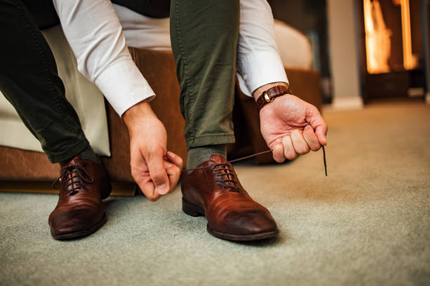 istock Elegant man tying shoelace at a hotel room, low angle image. 1365866144