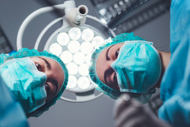 手術室で明るい光の下に立っている間専門の用具を使用して医学の制服の下から女性の外科医から。高品質の写真 - scrubs surgeon standing uniform ストックフォトと画像