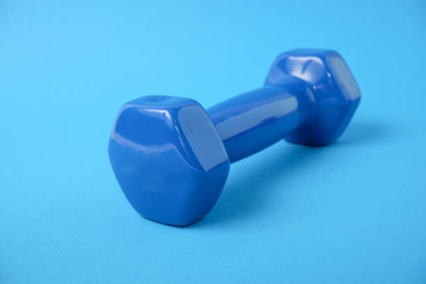 istock Dumbbells in a plastic sheath on a blue background. Sports inventory. Training workout equipment. Sport and exercises. 1365871176