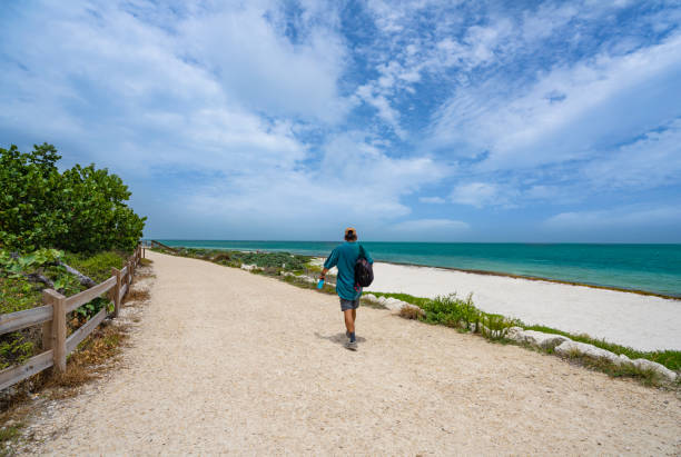 istock Man walking along beautiful Florida beach. 1365871395