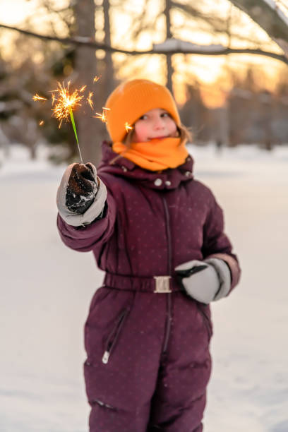 istock cute girl keeps a sparkler in winter in forest 1365871560