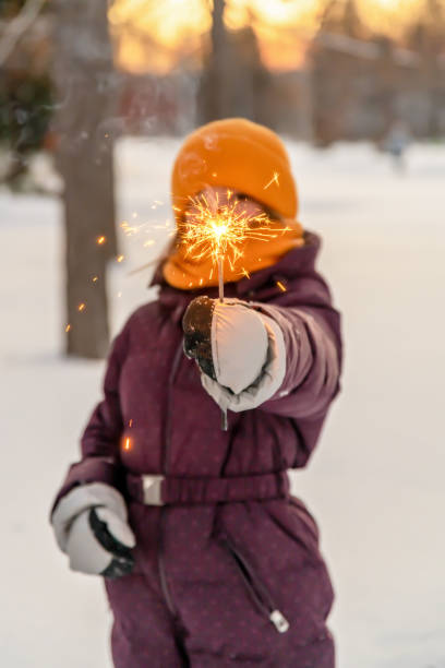istock cute girl keeps a sparkler in winter in forest 1365871634