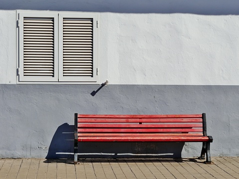 Park bench in the sunlight in front of a façade