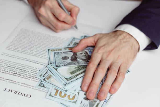 istock Man signing contract and hold hand on money 1365873075