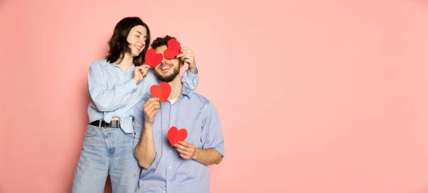 flugblatt. junger und glücklicher mann und frau mit grußkarten geformte herzen isoliert auf rosa trendigen farbhintergrund. emotions-, jugend-, liebes- und lifestyle-konzept - women isolated jumping 20s stock-fotos und bilder