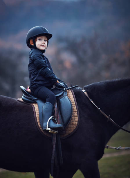 istock young boy, kid rider stays confidently during horse back ride 1365876077