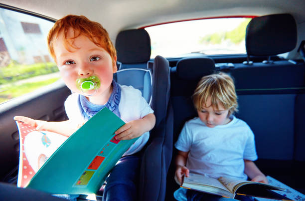 istock young kids sitting on back seat, reading book while traveling in the car 1365876434