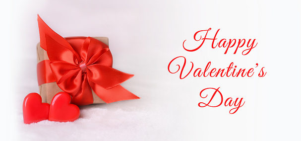Valentine's Day background. Gift box with a red bow and two hearts on a white background. Valentines day concept.Happy Valentine's Day.Copy space. Banner