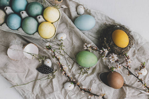 istock Stylish rustic Easter flat lay. Natural dyed colorful eggs, cherry blossoms, feathers and nest composition on linen cloth on white rustic table. Happy Easter! Countryside still life 1365878313