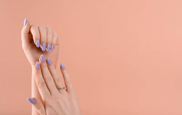 dłonie pięknego zadbanego fioletowego lakieru żelowego do paznokci lawendowych na beżowym tle - toenail zdjęcia i obrazy z banku zdjęć