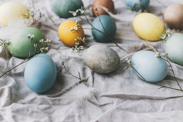 istock Easter eggs on rustic linen napkin with tender flowers. Happy Easter! Stylish natural dyed pastel colorful egg, spring flowers and feathers composition. Rustic still life 1365879414
