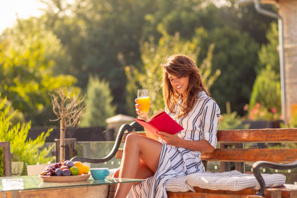 istock Woman drinking orange juice and reading a book 1365879496