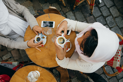 Two women friends sitting in a bar enjoying a hot coffee