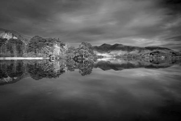 istock Black and white Absolutely stunning vibrant Autumn sunrise landscape image looking from Manesty Park in Lake Distict towards sunlit Skiddaw Range with mit rolling across Derwentwater surface 1365883582