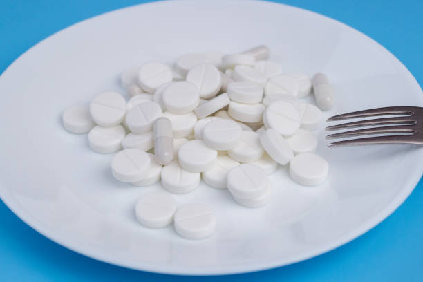 istock A bunch of medcin tablets with a fork on a plate on a blue background 1365885409