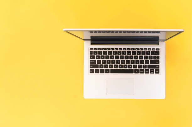 istock Open laptop on yellow background. top view. place for text. online education concept or remote work at home 1365886402