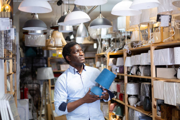 istock Man is choosing new table lamp for her home in store 1365887281