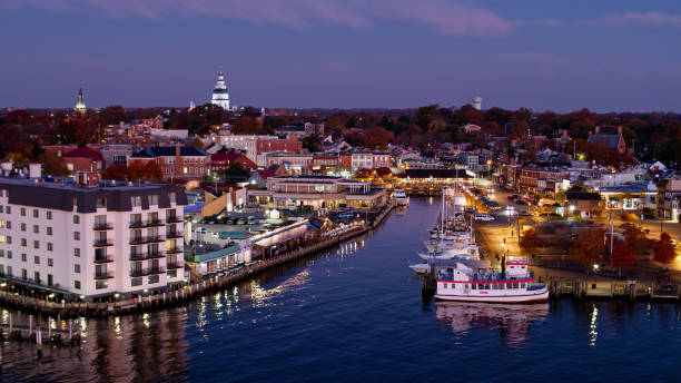 Waterfront in Annapolis, MD Before Sunrise - Aerial Aerial shot of Annapolis, Maryland before sunrise from over the harbor, looking over boats moored in the city dock towards the illuminated dome of the State House rising over trees with colorful autumn leaves. maryland us state photos stock pictures, royalty-free photos & images