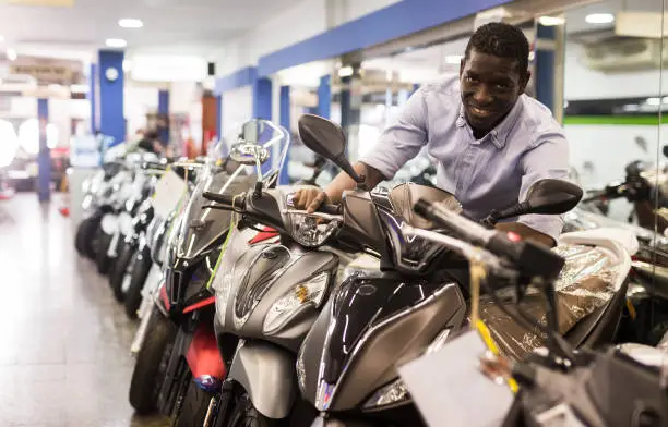 Afro american man is shopping and choosing new motobike in moto store