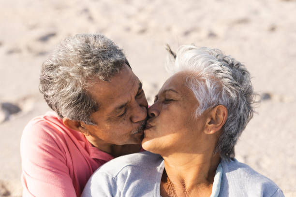 istock Affectionate multiracial senior couple kissing on lips while enjoying sunny day at beach 1365891427
