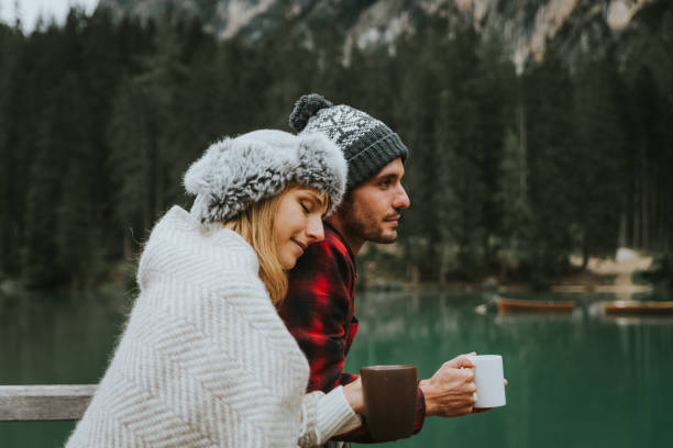 ritratto di una coppia romantica di adulti in visita a un lago alpino a braies in inverno. turista innamorato di bere caffè caldo in montagna. coppia, voglia di viaggiare e concetto di viaggio. - coffee couple italy drinking foto e immagini stock