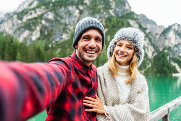 piękna para młodych dorosłych robiących selfie w zimie alpejskie jezioro - szczęśliwi turyści odwiedzający jezioro braies, włochy - koncepcja podróży, stylu życia i wędrówki - skiing people men women zdjęcia i obrazy z banku zdjęć