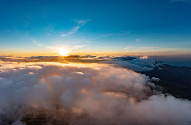 istock Sun shining brightly above white fluffy clouds at sunrise 1365893143