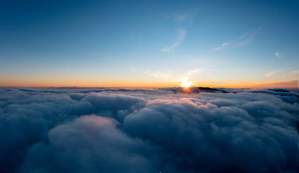 istock Sun shining brightly above white fluffy clouds at sunrise 1365893181